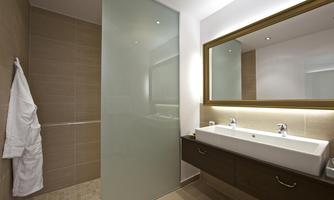 A modern bathroom with a glass shower and a large mirror. The walls are in neutral color tones, and there is a comfortable towel.