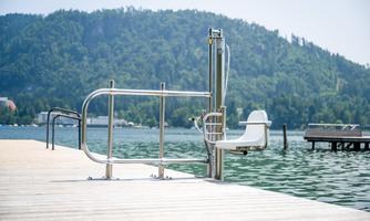A jetty by the water with a special aid for entry. In the background, green mountains stretch out.