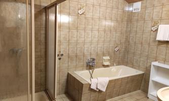 A modern bathroom with a shower and a bathtub. The walls are tiled with brown tiles and there are white towels.