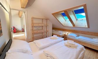 A cozy room with two beds and a skylight. The wooden shelves and the bright decor give the space an inviting atmosphere.