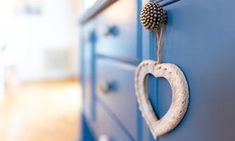 A close-up of a blue piece of furniture with a heart-shaped decoration. The texture of the heart and the buttons are clearly visible.