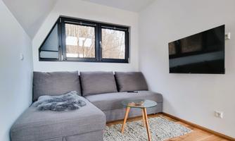 A cozy living space with a gray sofa and a small table. The large windows allow plenty of light in and provide a view outside.