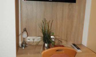 A beautiful desk area with a television on the wall. On the table, there is a lamp and a plant.