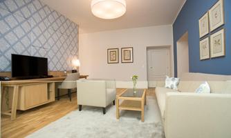 A modern living room with a television and a cozy couch. The walls are painted in calm colors, and there are decorative pictures.