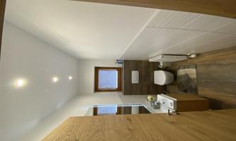 A modern bathroom with wood and tile accents. It includes a toilet, a sink, and a window for natural light.