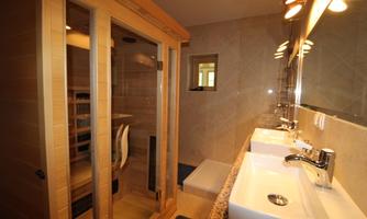 A modern bathroom with a sauna and two sinks. The walls are painted in neutral colors, and there is plenty of natural light.