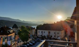 A picturesque view of a city by the water at sunset. The mountains are visible in the background, and the atmosphere is calm and inviting.