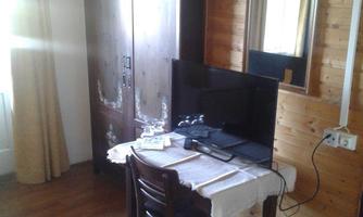 A cozy room with a wooden floor. A table with a television and a cabinet on the wall.