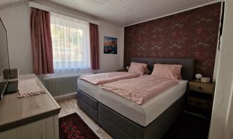 A cozy bedroom with a double bed and harmonious colors. Large windows provide plenty of daylight.