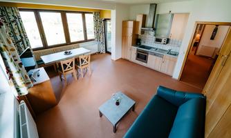 A bright and modern apartment with an open kitchen and dining area. Large windows offer a view of the surroundings and let in plenty of light.