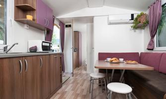 A modern, bright mobile home with a kitchenette and a dining area. The space is cozily furnished and offers an inviting stay.