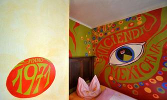 A vividly designed room with colorful Mexican murals. Noteworthy are the eye and the year 1971, which give the room a creative atmosphere.