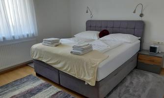 A cozy bedroom with a large double bed and fresh towels. The room is bright and friendly with a modern design.