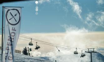 A ski resort with chairlifts and a snow-covered slope. In the background, a blue sky is visible.