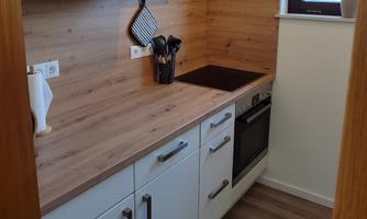 A modern kitchen with wood paneling and white cabinets. The room is clean and well-organized.