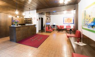 An elegant hotel reception with wooden decor and a red carpet. Cozy seating completes the friendly ambiance.