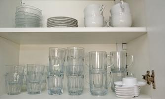 A kitchen shelf with various jars, cups, and dishes. The items are neatly stacked and in bright colors.