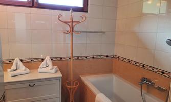 A modern bathroom with a bathtub and neatly folded towels. Bright tiles and large windows create a friendly atmosphere.