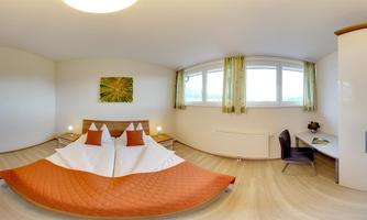 A modern hotel room with a large bed and bright walls. There is a window with a view outside and a desk in the corner.