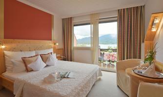 A cozy bedroom with a large bed and bright walls. The room offers a beautiful view of the mountains through the window.