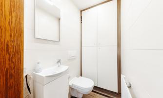 A modern bathroom with a white sink and toilet. There is also a mirror and a cabinet on the wall.
