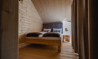 A cozy bedroom with wooden walls and a double bed. The room has an inviting atmosphere and is well lit.