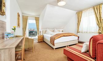 A cozy room with a large bed and a comfortable seating area.  
Large windows provide plenty of daylight and a view outside.