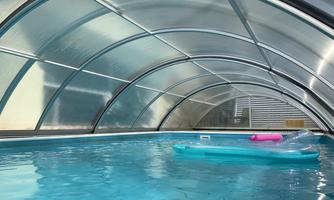 A swimming pool with clear, blue water. A pink air mattress is floating in the pool.