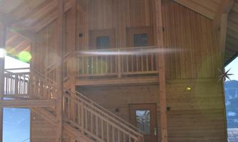 A beautiful wooden house with a large balcony and an outdoor staircase. The clear sky makes the building shine brightly.