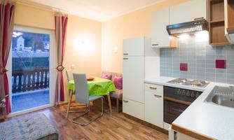A cozy kitchen with a dining area and modern appliances. A window offers a view of a balcony and provides plenty of light.