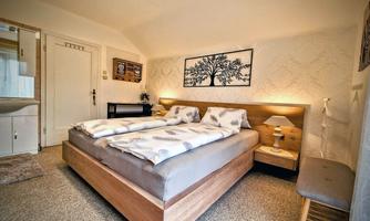 A cozy bedroom with two beds and bright decor. A picture of a tree hangs on the wall.