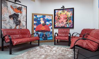 A cozy room with red leather furniture. Colorful artworks hang on the walls.