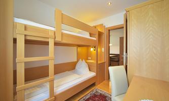 A cozy room with bunk beds and a desk. The room is bright and furnished in a modern style.