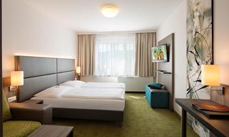 A modern bedroom with two single beds and elegant furnishings. A television and a stylish piece of art complete the room.