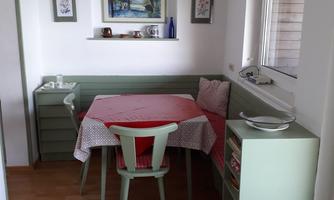 A cozy dining kitchen with a table and a bench. The walls are bright and decorated with decorative pictures.