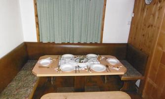 A cozy dining area with wooden paneling and a set table. On the table are plates and cutlery prepared for several people.