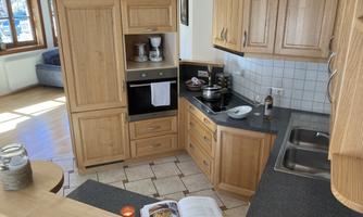 A modern kitchen with wooden cabinets and an elegant work area. On the countertop are a cookbook and various kitchen utensils.
