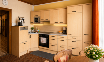 A modern kitchen with wooden cabinets and a bright countertop.  

On the table, there is a flower plant and a cozy atmosphere.