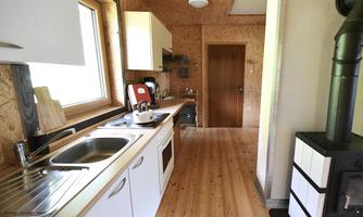 A modern kitchen with wooden flooring and white cabinets. It is well equipped with windows for natural light.