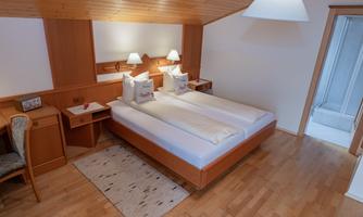 A cozy bedroom with two single beds and wooden furniture. The soft lighting creates an inviting atmosphere.