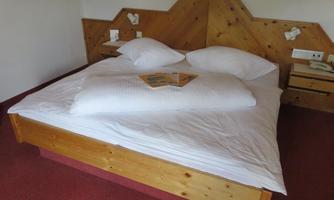 A cozy bedroom with a large wooden bed and white pillows. Several informational brochures are lying on the bed.