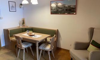 A cozy dining area with a round table and four chairs. Pictures hang on the wall, and a lamp provides pleasant light.