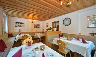 A cozy restaurant with a wooden beam ceiling and tables covered with white tablecloths. The rooms are cheerfully decorated and invite you to linger.