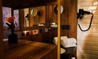 A stylish bathroom with a wooden washbasin and a large mirror. 

On the wall, a hairdryer and neatly arranged towels are hanging.