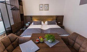 A modern bedroom with a double bed and elegant furnishings. Fresh fruit and decor are on the table.