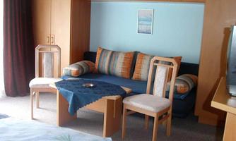 A cozy room with a small seating area and colorful cushions. Two chairs and a table complement the inviting atmosphere.