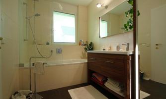 A modern bathroom with a bathtub and a shower. The room has bright walls and a large mirror.