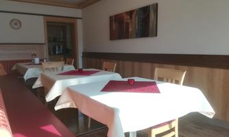 A cozy room with several tablecloths and red placemats. The room has wooden paneling and a decorative picture on the wall.