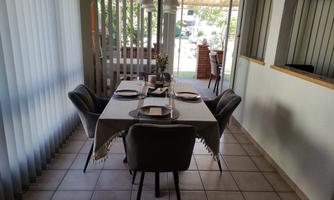 A bright dining room with an elegant table and chairs. The large window front lets in plenty of daylight.
