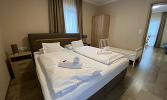 A cozy bedroom with a double bed and a crib. Soft colors and plenty of light create an inviting atmosphere.